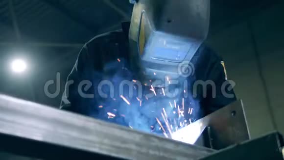 在工作期间在防护头盔中关闭焊工在焊接厂工作的专业重工焊工视频的预览图