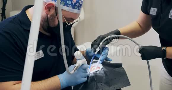 男牙医在办公室工作两个牙医做空气流动牙齿清洁视频的预览图