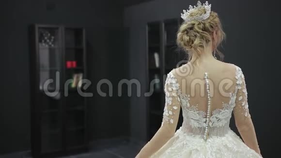 身穿白色婚纱的金发新娘头戴皇冠在房间前走视频的预览图