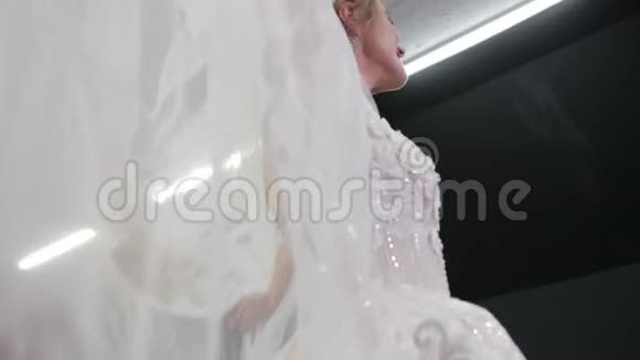 新娘身穿白色婚纱头戴皇冠手拿面纱把它展开视频的预览图