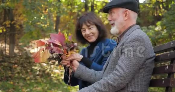 快乐的老夫妻在市中心公园的长椅上交流和放松看看秋天视频的预览图