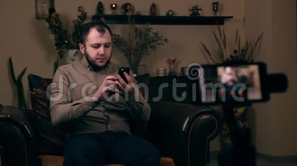 这位颇具影响力的留胡子的年轻人一位来自欧洲的博客作家坐在椅子上录制视频笑着视频的预览图