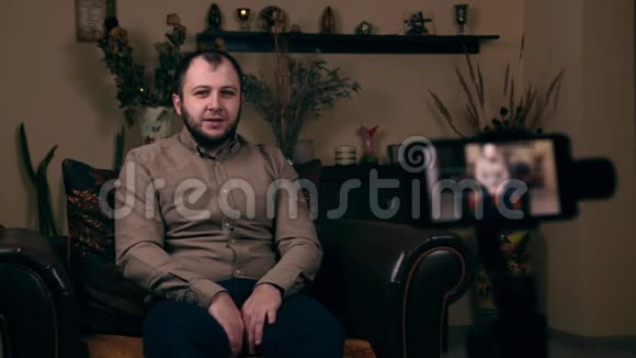 这位颇具影响力的留胡子年轻人一位来自欧洲的博客作者穿着衬衫坐在椅子上录制了一段视频视频的预览图