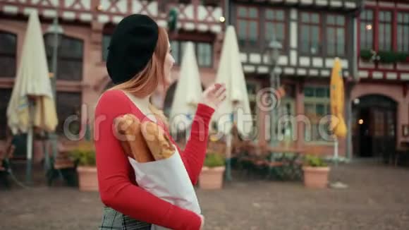 一个戴着黑色贝雷帽手里拿着纸包面包的法国女孩微笑着视频的预览图