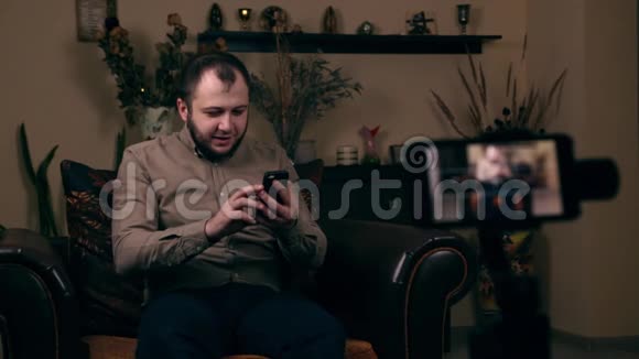 这位颇具影响力的留胡子的年轻人一位来自欧洲的博客作者坐在椅子上录制视频笑着视频的预览图
