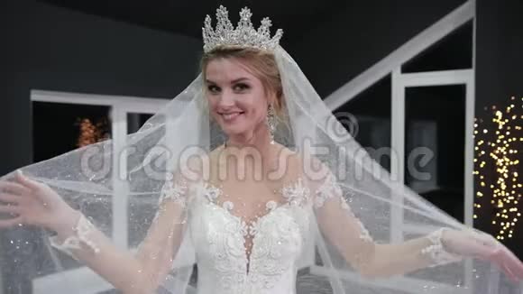 新娘头上戴着皇冠双手戴着面纱对着镜头微笑使她变得轻松视频的预览图