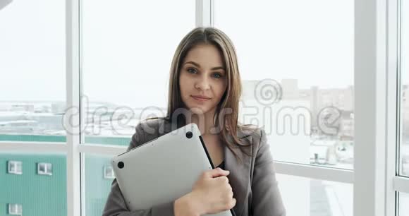女商人的肖像和笔记本办公室附近窗口的漂亮女性行政人员视频的预览图