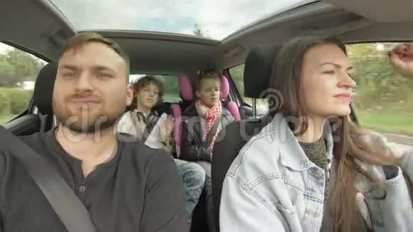 幸福的爱的父母和他们兴奋的孩子微笑着在城市里开车年轻家庭旅行视频的预览图