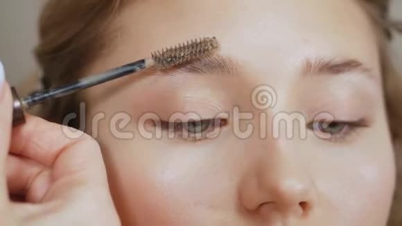 化妆师在客户脸上化妆用硅胶刷梳理眉毛视频的预览图