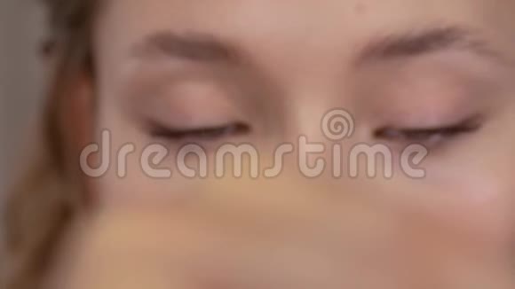化妆年轻女孩看着镜子用刷子在眼睛的睫毛上涂上睫毛膏视频的预览图
