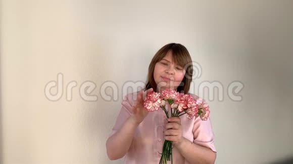 女人拿着一束粉红色的康乃馨花看着它们用手触摸节日的概念情人节视频的预览图