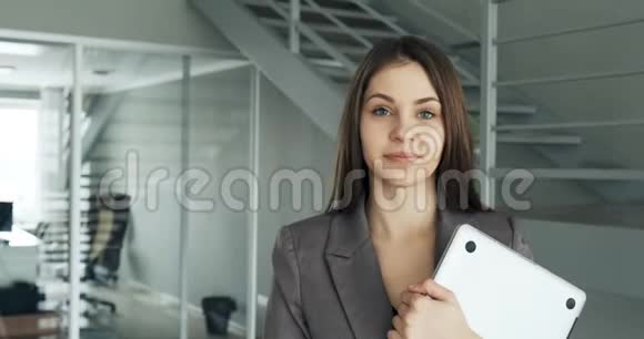 年轻的商务女性走在办公室走廊里有魅力的女性会带着笔记本和视频的预览图