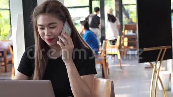 美丽迷人的亚洲商务女性在咖啡厅使用智能手机或手机微笑和快乐视频的预览图