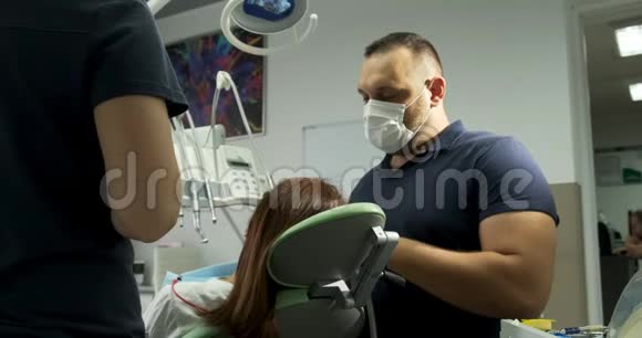 男牙科医生和办公室的病人一起工作视频的预览图
