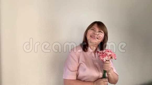 女人闻着一束粉红色的康乃馨微笑节日的概念情人节母亲视频的预览图