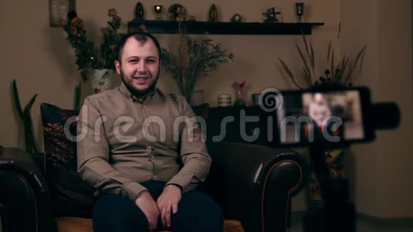 一位颇具影响力的留胡子年轻人一位来自欧洲的博客作家坐在椅子上穿着衬衫正在录制一段视频视频的预览图