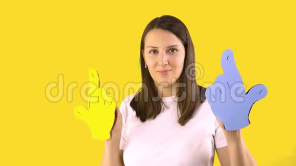 一个穿着白色T恤的女人正在黄色背景上跳舞里拿着蓝色和黄色的卡通手乐趣视频的预览图
