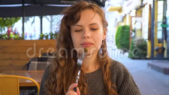 年轻女子在街头咖啡馆吃巧克力树锥特写视频的预览图