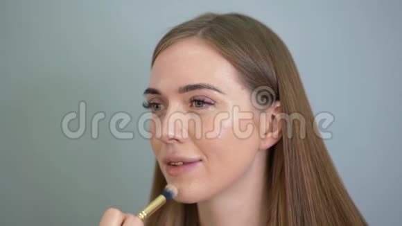 化妆师用画笔将粉底涂在女人的脸上沙龙视频的预览图