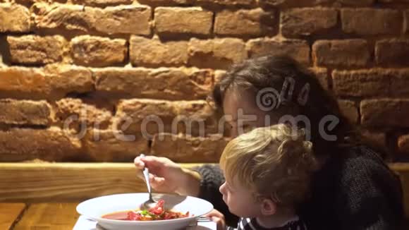 年轻女子带着小男孩在餐厅酒吧吃新鲜汤视频的预览图