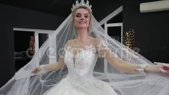 新娘头上戴着皇冠双手戴着面纱对着镜头微笑使她变得轻松视频的预览图