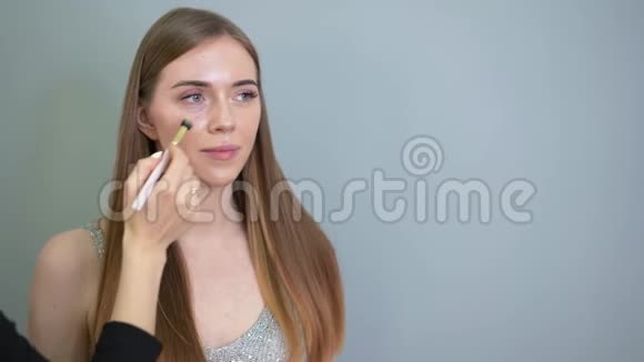 化妆师用画笔将粉底涂在女人的脸上沙龙视频的预览图
