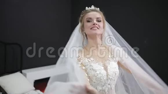 年轻的新娘穿着白色婚纱玩着面纱拍着微笑的相机视频的预览图