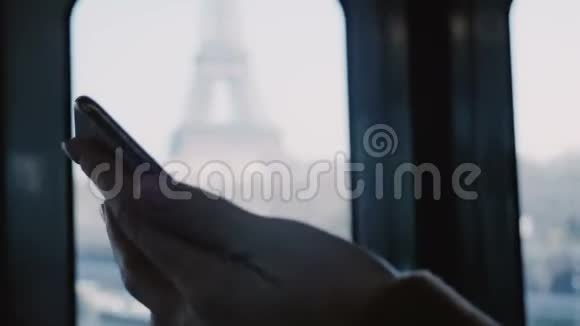 用智能手机在移动地铁列车车门上观看女性手的电影特写镜头埃菲尔铁塔景观慢动作视频的预览图