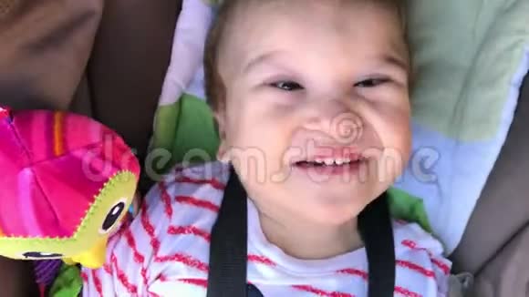 可爱的残疾婴儿在推椅与玩具微笑和看相机残疾儿童有特殊需要的孩子谷物视频的预览图