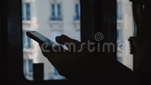 黑暗的电影特写女性手的轮廓使用智能手机在移动地铁车门窗口慢动作视频的预览图