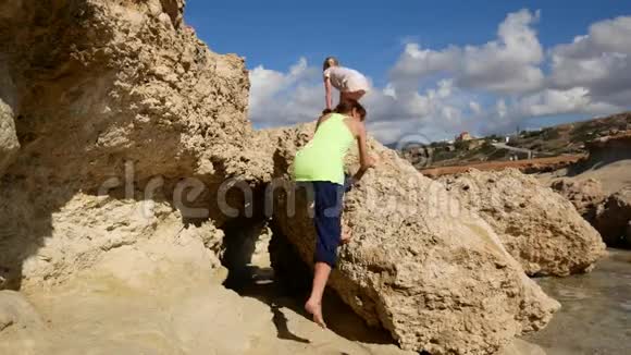 妈妈和宝宝爬上地中海沿岸的悬崖塞浦路斯视频的预览图