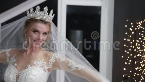 新娘头上戴着一顶皇冠为照相机摆姿势用面纱遮住她的脸视频的预览图
