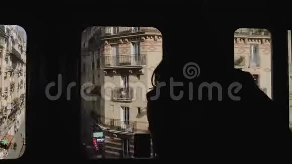 快乐美丽的女游客乘坐巴黎地铁列车透过窗户观看城市建筑的剪影视频的预览图