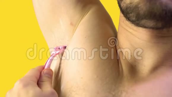 一个年轻人用粉红色的织布机把他的腋窝剃了特写视频的预览图