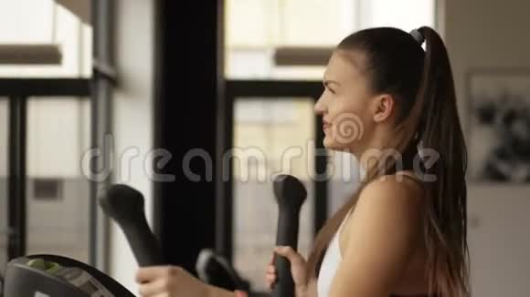 健身妇女在健身房的运动模拟器上训练腿部肌肉在体育俱乐部受过训练的女孩视频的预览图