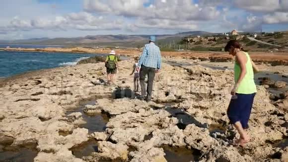 游客沿着陡峭松散的石灰石海岸沿着大海散步视频的预览图