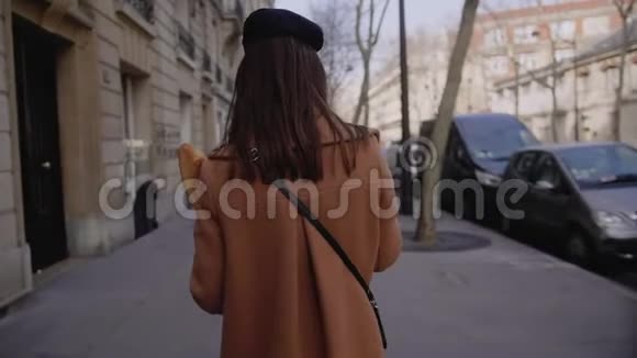 镜头跟随美丽优雅幸福的女人走在巴黎街头带着纸购物食品袋慢动作视频的预览图