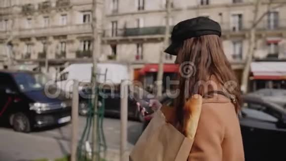 侧观美丽优雅的美食博主女人走在巴黎大街上带着生态纸购物袋慢动作视频的预览图