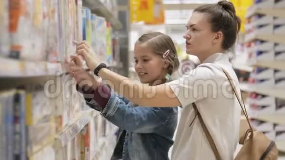 快乐的女孩子和她迷人的母亲在超市里一起选择餐桌游戏视频的预览图