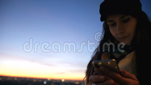 低角度特写年轻漂亮的当地女人使用智能手机应用程序在令人难以置信的明亮日落背景缓慢运动视频的预览图