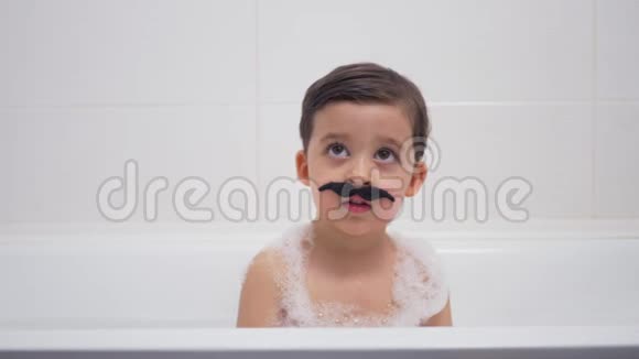 一个留着黑胡子的小男孩坐在浴室里视频的预览图