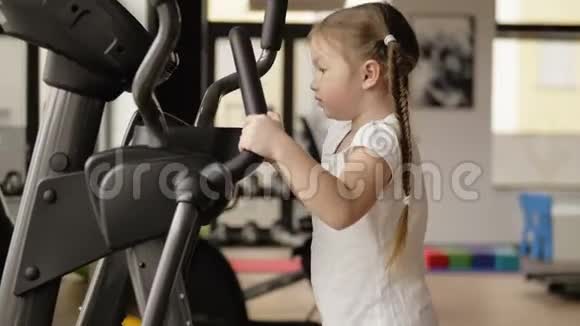 这个小女孩在一个有模拟器的健身房里工作健身运动服的概念视频的预览图