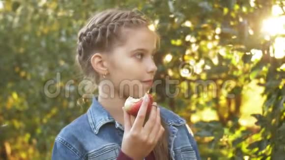 可爱的女孩肖像留在苹果花园户外吃成熟多汁的水果视频的预览图