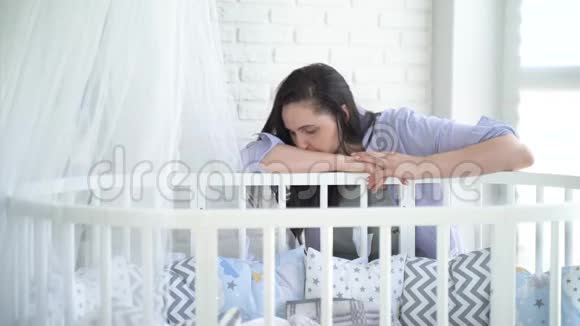不开心的女人年轻的母亲烦恼疲惫的女人睡在婴儿床旁视频的预览图