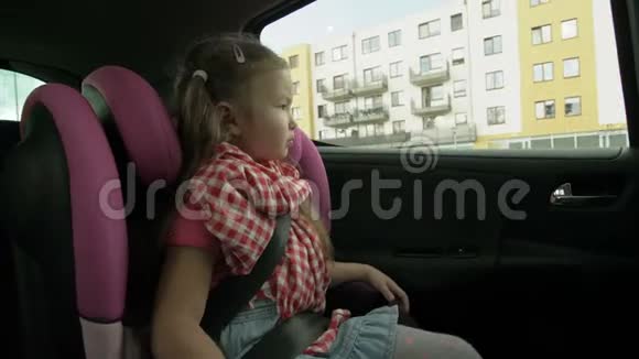 可爱的小女孩坐在后座上透过窗户看着车视频的预览图