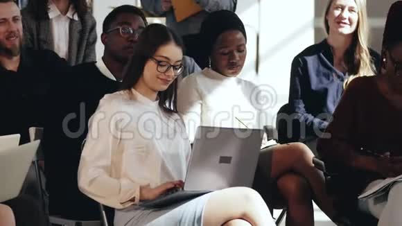 快乐微笑的年轻白种人商务女性坐在多民族观众中在会议研讨会上为演讲者鼓掌视频的预览图