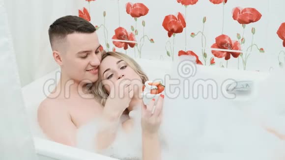 这对夫妇躺在浴缸里有泡沫草莓和奶油视频的预览图
