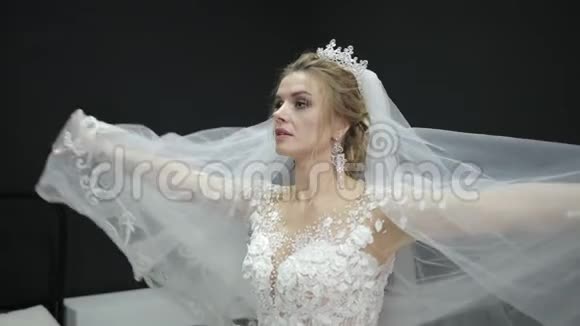 年轻漂亮的新娘穿着白色婚纱玩面纱掀起波澜视频的预览图