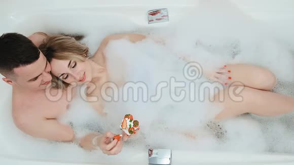 这对夫妇躺在浴缸里里面放着泡沫草莓和奶油视频的预览图