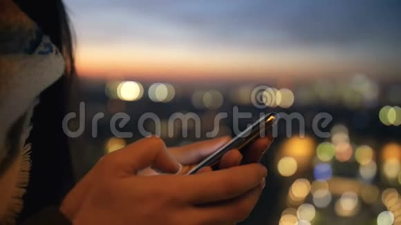 stadicam在美丽的bokeh夕阳城市背景下用智能手机移动办公室在女性手上做特写视频的预览图